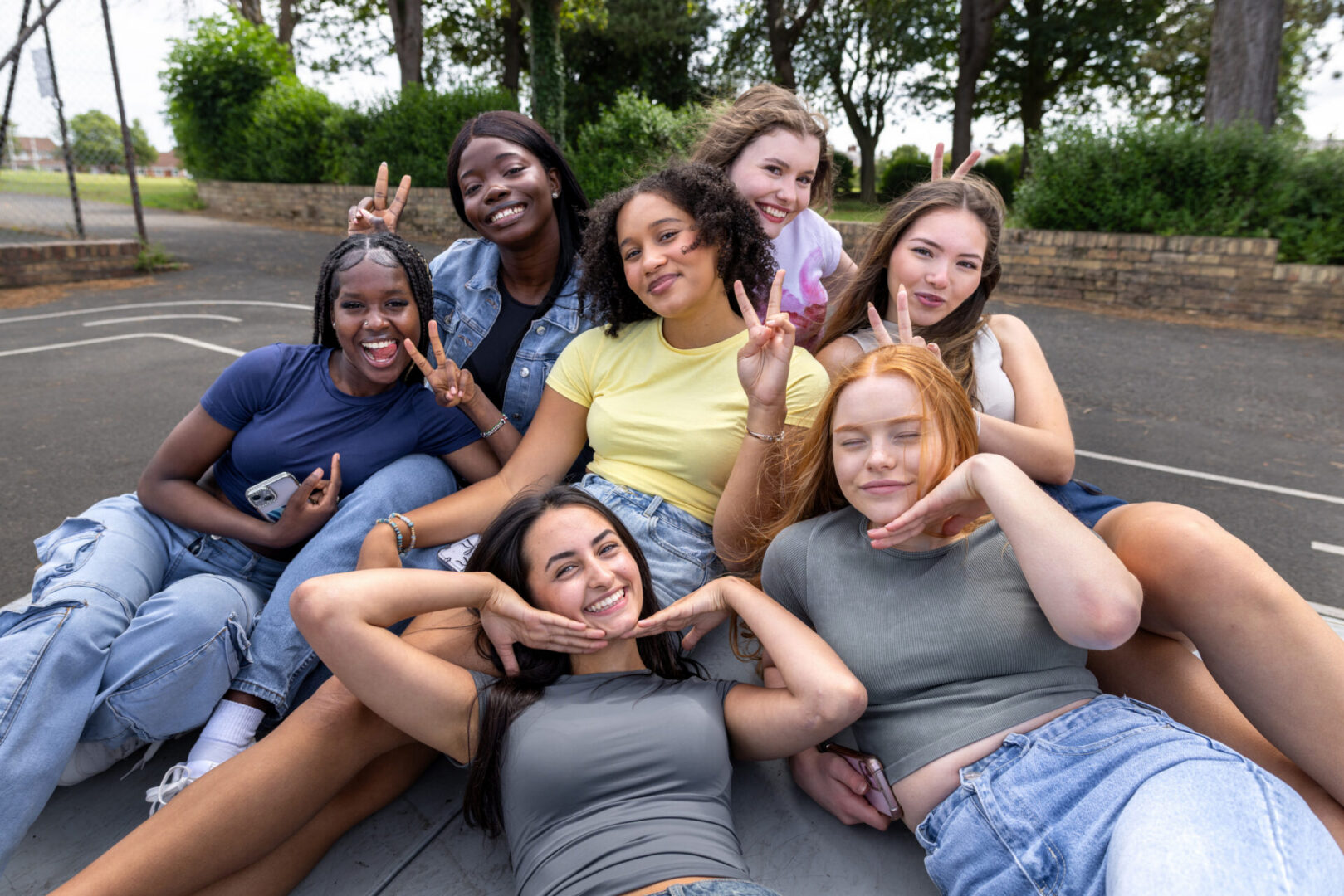 Medium shot of a group of teenage friends hanging out on a bicycle ramp beside a sports court in Newcastle-upon-Tyne, North East England. They are all wearing casual clothing, reclining and huddled together, smiling and gesturing towards the camera.

Videos similar to this scenario available.
